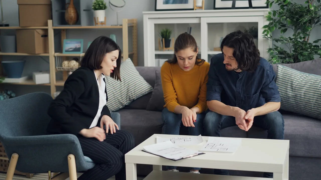 Energieberater bespricht Grundrisse mit einem Paar im Wohnzimmer